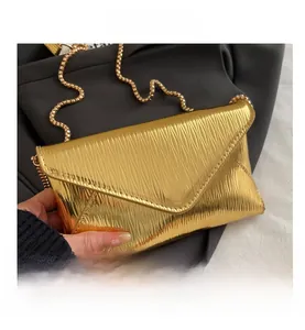 Detail of the golden envelope chain bag featuring a luxury textured wave pattern surface