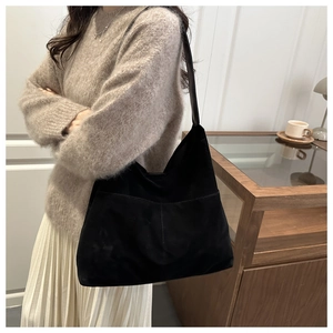 Close-up of a large black suede hobo bag with leather straps and central stitching