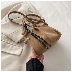 Close-up of brown suede handbag featuring pleated texture and silver heart pendant