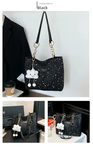 Detail of black star print tote bag with metal chain strap and white plush cloud charm