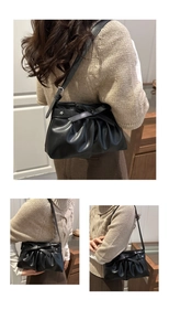 Detail of black pleated shoulder bag featuring a leather bow and silver star ornament
