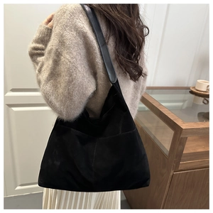 Close-up of a large black suede tote bag with elegant vertical stitching for women