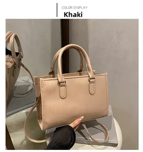 Detailed close-up of khaki textured leather handbag with silver hardware and vertical stripes