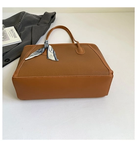 Détail macro du sac cabas en cuir marron avec texture litchi et accessoire foulard en soie