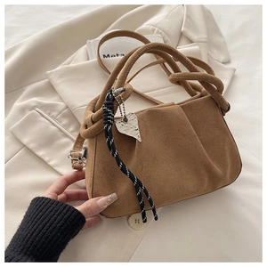 Detail of retro brown suede handbag featuring knotted handle and silver heart charm