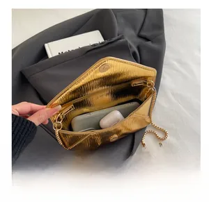 Detail showing the internal storage capacity of the gold envelope chain bag with accessories