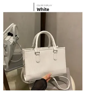Detail of white leather tote bag featuring vertical embossed texture and detachable strap