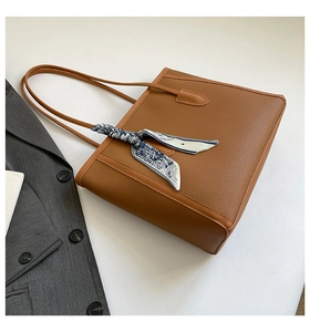 Détail du sac cabas marron texture lychee avec foulard en soie sur une veste de costume