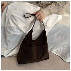 Detail of a dark brown suede hobo bag featuring two vertical pockets and slim leather straps