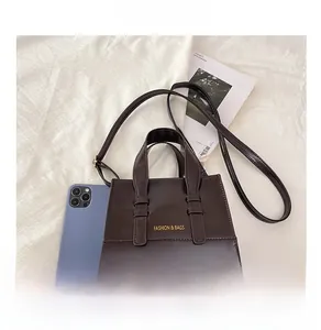 Detail view of mini dark brown crossbody bag with phone for size reference