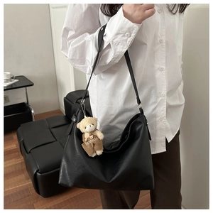 Dettaglio borsa bowling in ecopelle nera con ciondolo a forma di orso e metalleria