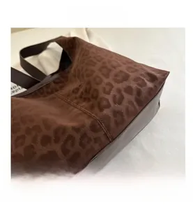 Close-up of leopard print fabric texture and brown leather stitching on the tote bag