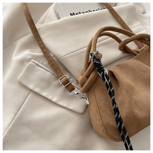 Detailed view of brown suede handbag featuring a unique knotted handle and woven cord detail