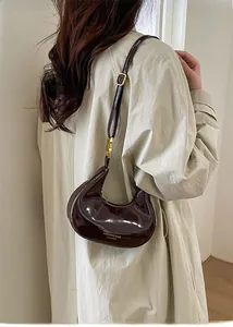 Dettaglio di una borsa a mezzaluna marrone scuro in vernice lucida con dettagli dorati