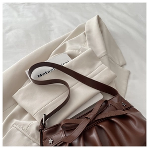 Detail of dark coffee bow tote with pleated leather texture and silver star accents