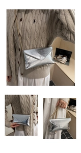 Detail view of silver envelope crossbody bag with textured metallic finish and gold chain strap
