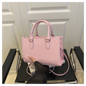 Dettaglio della borsa tote in pelle PU rosa plissettata con strisce e tracolla sottile