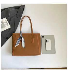 Détail du cabas en cuir grainé marron avec foulard en soie et accessoires de bureau