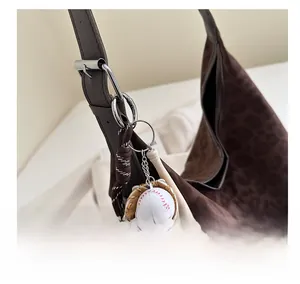 Detail of creative baseball keychain with glove and bat on a leopard print tote bag