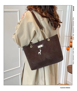 Detail of dark brown matte leather tote bag with gold chain strap and deer pendant