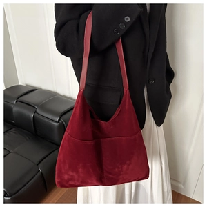 Detail of burgundy suede tote bag featuring large outer pockets and matte finish texture