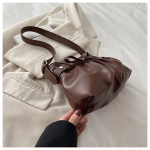 Detail of dark brown pleated tote bag with bow drawstring and silver star charm pendant