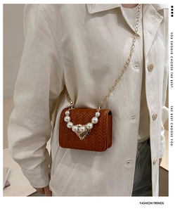 Detail of woven brown mini flap bag featuring decorative pearls and gold chain strap