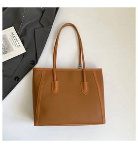 Gros plan sur le sac cabas en cuir marron à motif litchi avec détails lisses