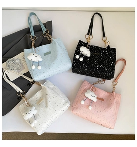 Flat lay of tote bags with silver star patterns, chain handles and plush cloud charms