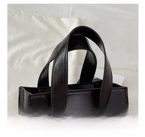 Detailed close-up of dark brown wax leather handles and metal hooks on luxury tote bag
