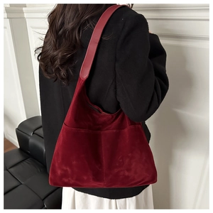 Close-up of burgundy hobo shoulder bag featuring suede texture and dual front pockets