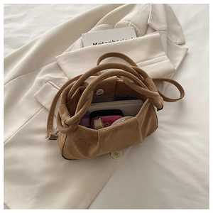 Detailed view of brown suede handbag featuring knotted handles and magnetic closure