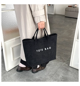Close-up of black matte tote bag with white TOTE BAG text print and dual handles