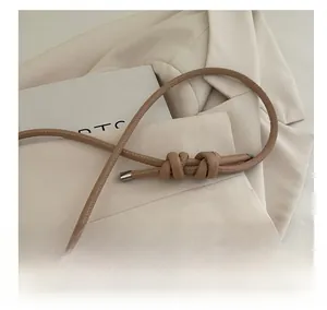 Detail view of beige shoulder bag with knotted leather strap and pearl chain accent