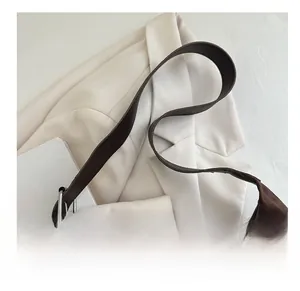 Detail of dark brown shoulder bag with metal rings and decorative sports charm