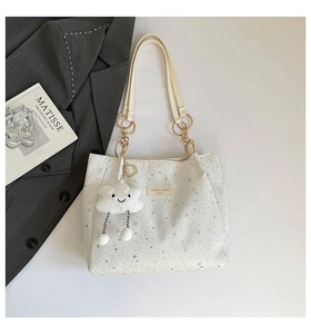 Detail of star-patterned tote bag with golden chain and cloud plush charm detail