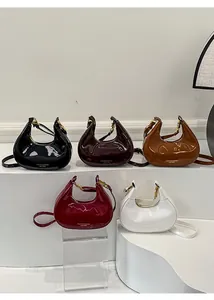Dettaglio di borse a mezzaluna in vernice multicolore con finitura lucida e finiture dorate