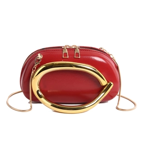 Chic red crescent handbag with large gold circular handle and crossbody chain strap