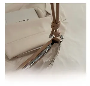 Detail of the smooth metallic zipper and knot design on this minimalist beige shoulder bag