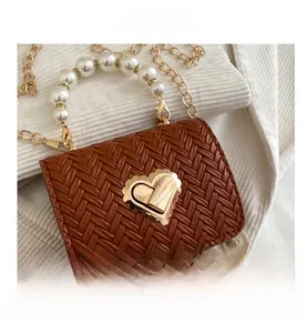 Detail of woven straw handbag with a golden heart clasp and elegant pearl handle