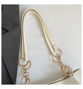 Detail of white tote bag featuring silver star print and gold metal ring strap connectors
