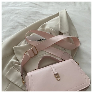 Detail of light pink crossbody square bag with wide fabric strap on beige blazer