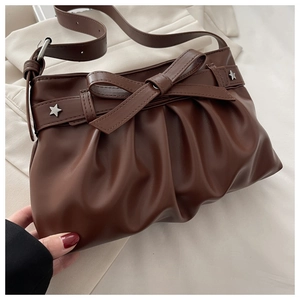 Detail of dark brown pleated tote bag featuring large bow and silver star studs