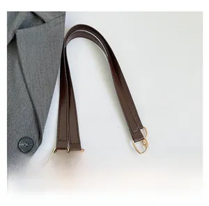 Detail of deep brown faux leather handbag showing golden metal ring and chain strap