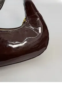 Dettaglio della borsa hobo in vernice marrone scuro con finitura lucida e zip dorata
