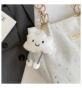 Detail of soft white cloud plush charm with smiling embroidery on a fashion tote bag