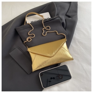 Detail of gold envelope bag featuring epi water ripple texture and metallic chain strap