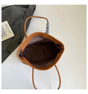 Détail du cabas en cuir fauve avec foulard en soie au manche et poche intérieure zippée