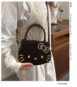 Detail of dark brown suede cartoon cat handbag with gold embroidery and leather strap