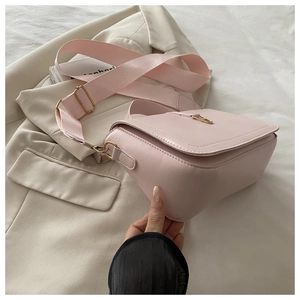 Detail view of pink crossbody square bag with wide fabric strap and gold metal buckle